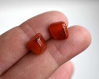 May include: Two small, smooth, orange carnelian stones. The stones are tumbled and have a polished finish.