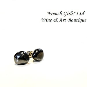 May include: A pair of black gemstone stud earrings. The earrings are round and have a smooth, polished finish.