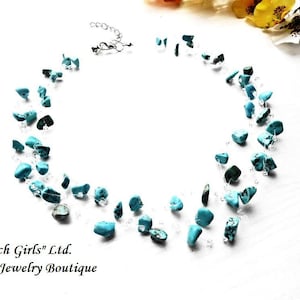 May include: A turquoise gemstone necklace with a silver chain. The necklace is made of small, irregular shaped turquoise stones. The stones are strung on a silver chain and are separated by small silver beads. The necklace is a beautiful and unique piece of jewelry.