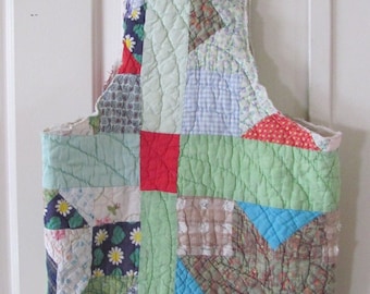May include: A patchwork quilt tote bag featuring a range of colours and patterns, including green, red, blue, and white. The bag is crafted from quilted fabric and has a straightforward design.