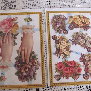 Peut inclure: Deux feuilles de papier avec des motifs floraux vintage. L'une représente des mains tenant des roses et des pensées, l'autre des brouettes débordant de fleurs. Les deux ont une bordure dorée et un motif quadrillé bleu.