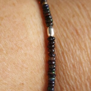 May include: A bracelet made of small, dark, iridescent beads with a silver clasp.