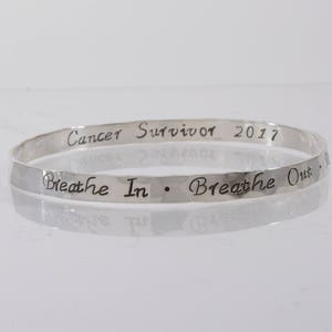 Könnte beinhalten: Silberner Armreif mit der Inschrift "Cancer Survivor 2017 Breathe In. Breathe Out."