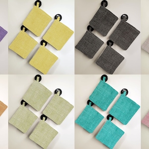 May include: Set of four square pot holders in various colors, including purple, yellow, orange, green, turquoise, beige, and pink. The pot holders are made of a textured fabric and have a loop for hanging.
