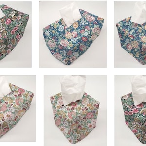 May include: Six tissue box covers with different floral patterns. The covers are made of fabric and have a square shape. The patterns include pink, green, blue, and white flowers.