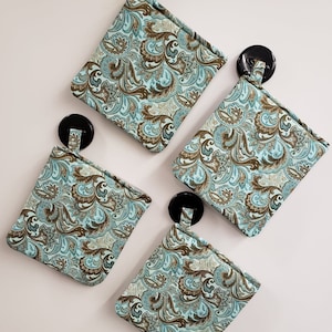 May include: Four teal blue and brown paisley patterned pot holders with black button loops.