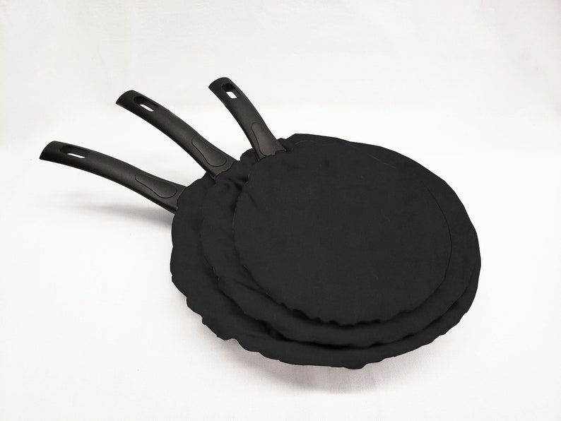 May include: Three black non-stick frying pans stacked on top of each other.