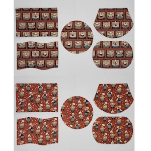 May include: Set of eight red and black fabric placemats with a variety of designs featuring chefs, food, and text. The placemats are in different shapes, including round, oval, and rectangular.