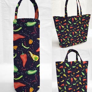 May include: A set of three fabric bags with a dark blue background and a colorful chili pepper pattern. The bags include a wine bottle bag with a handle, a tote bag, and a smaller tote bag, all featuring the same design.