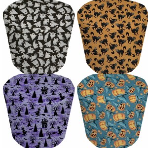 May include: Four different Halloween-themed fabric designs. The first design features white ghosts on a black background. The second design features black cats on a yellow background. The third design features black witches and trees on a purple background. The fourth design features orange pumpkins on a blue background.