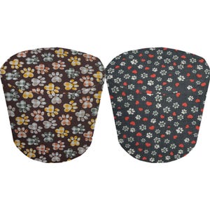 May include: Two fabric dog bowl covers. One is brown with paw prints and plaid hearts. The other is dark gray with paw prints and red hearts.