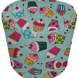 May include: A turquoise fabric with a repeating pattern of colorful cupcakes. The cupcakes are decorated with sprinkles, cherries, and strawberries.