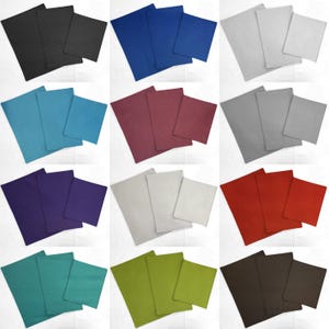 May include: Set of 12 placemats in various colors, including black, blue, teal, burgundy, gray, white, purple, red, green, and brown. Each set includes two placemats, one larger and one smaller.