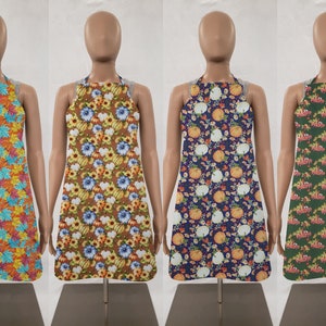 May include: Four different aprons with fall-themed prints. The aprons are on mannequins and have adjustable neck straps. The prints include colorful leaves, pumpkins, and flowers.