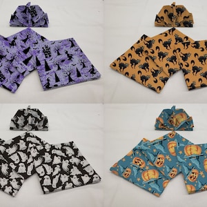 May include: Four sets of Halloween-themed fabric napkins. Each set includes two napkins with a different design. The designs include ghosts, pumpkins, black cats, and witches.