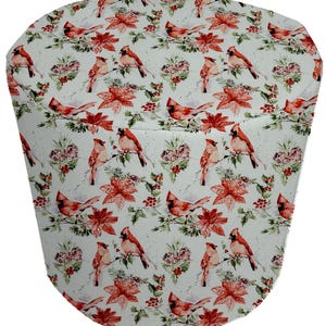 May include: White fabric with a repeating pattern of red cardinals, poinsettia flowers, and green foliage. The fabric has a subtle speckled texture.