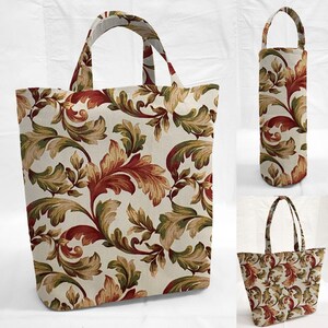 May include: Tote bag, wine bottle carrier, and small tote bag with a cream background and a repeating pattern of red, green, and tan leaves and vines. The bags have matching handles.
