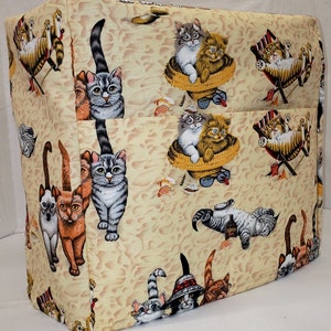 May include: A beige kitchen appliance cover with a repeating pattern of cats in various poses. The cats are depicted in shades of brown, gray, and white, and some are wearing sunglasses. The cover features a beach theme with seashells and palm trees.