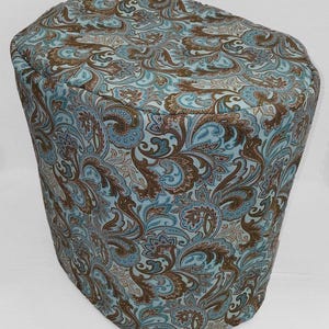 May include: A blue and brown paisley patterned fabric cover for a kitchen appliance.
