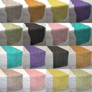May include: A collection of table runners in various colors, including beige, orange, yellow, purple, green, black, pink, and teal. Each runner is displayed on a white surface, showcasing their textures and hues.