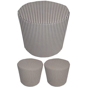 May include: Three matching cylindrical ottomans. The ottomans are covered in a fabric with a cream background and vertical navy blue stripes. The largest ottoman is upright, while the other two are smaller and placed below.