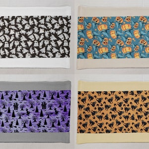 May include: Four Halloween-themed rectangular fabric panels. The panels feature various patterns: white ghosts on black, orange pumpkins and bats on blue, black witches and trees on purple, and black cats on orange.