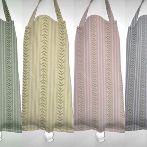 May include: Four striped fabric aprons with leaf designs. The aprons are in green, yellow, pink, and gray.