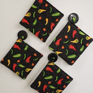 May include: Four black fabric pouches with a white polka dot pattern and a repeating design of red, yellow, and green chili peppers. Each pouch has a black button closure.