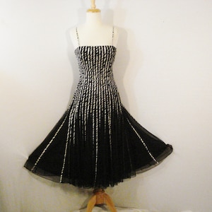 May include: A black and white striped sleeveless dress with a flowing skirt. The dress is on a white background.