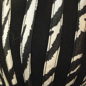 May include: Black and white striped fabric with a black mesh overlay. The fabric has a subtle sheen and is likely used for clothing or accessories.