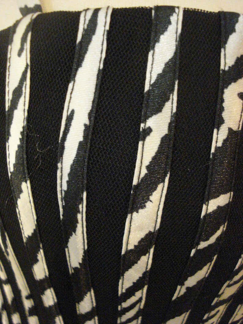 May include: Black and white striped fabric with a black mesh overlay. The fabric has a subtle sheen and is likely used for clothing or accessories.