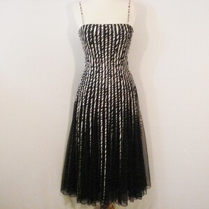 May include: A black and white striped sleeveless dress with a black tulle overlay. The dress has a fitted bodice and a flowing skirt.