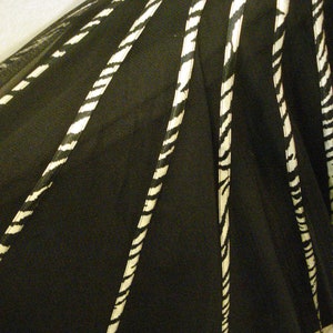 May include: Black and white striped fabric with a sheer texture. The fabric is gathered in a fan shape, creating a layered effect.