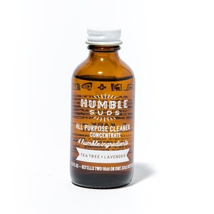 May include: A brown glass bottle with a white cap, labeled "HUMBLE SUDS ALL PURPOSE CLEANER CONCENTRATE 4 humble ingredients TEATREE + LAVENDER 1.5 FL OZ - REFILLS TWO 16OZ OR ONE 32OZ BOTTLE"