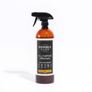 May include: A brown plastic bottle with a black spray nozzle. The bottle is labeled "Humble Suds All Purpose Cleaner" and "Sweet Orange - Clove".
