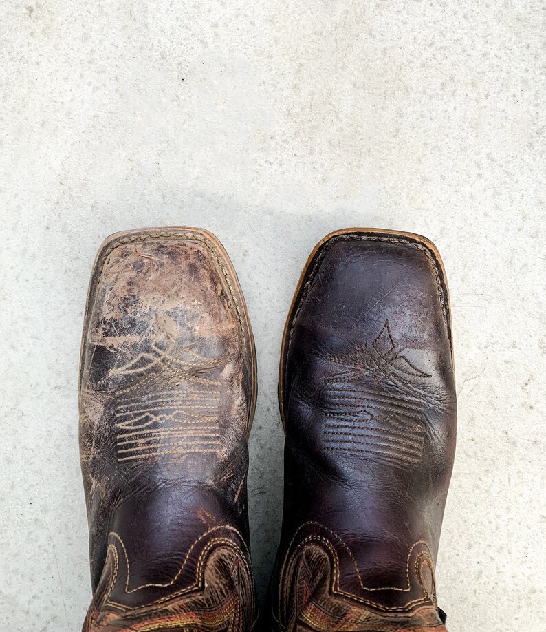 K&ouml;nnte beinhalten: Ein Paar braune Cowboy-Stiefel aus Leder mit aufwendigen N&auml;hten. Die Stiefel haben eine spitze Zehenpartie und einen leichten Absatz.
