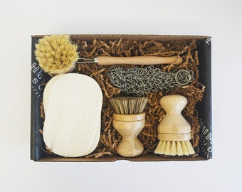 May include: A set of kitchen cleaning tools in a brown box with a black and white pattern. The set includes a sponge, a scrub brush, a wire scrubber, and a wooden brush with a handle.