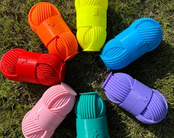 May include: Seven colourful yarn holders in a rainbow pattern. The holders are made of plastic and have a textured surface. Each holder has a small label with a graphic on it.