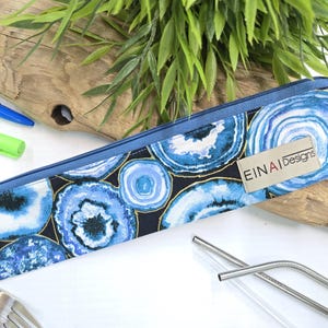 May include: A blue and gold zippered pouch with a pattern of blue agate slices. The pouch has a label that reads 'EINAI Designs'.