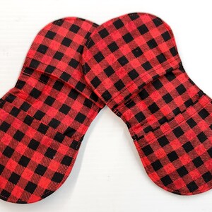 May include: Two red and black checked pot holders. The pot holders are shaped like an oval with a rounded edge.
