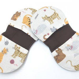 May include: Two brown fabric coin purses with a white background and a cat pattern. The purses are open to reveal a brown fabric interior.