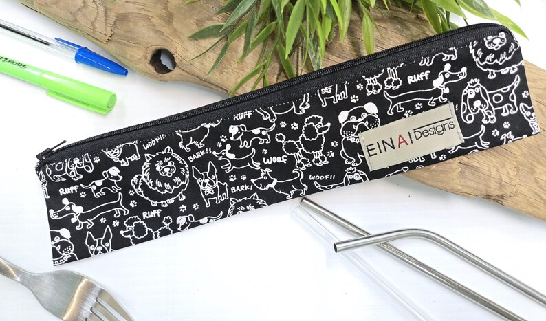 May include: Black zippered pouch with a white dog pattern and the text 'EIN AI Designs'. The pouch contains two silver metal straws.