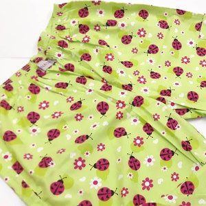 May include: Green pyjama trousers with a white and pink ladybug print.