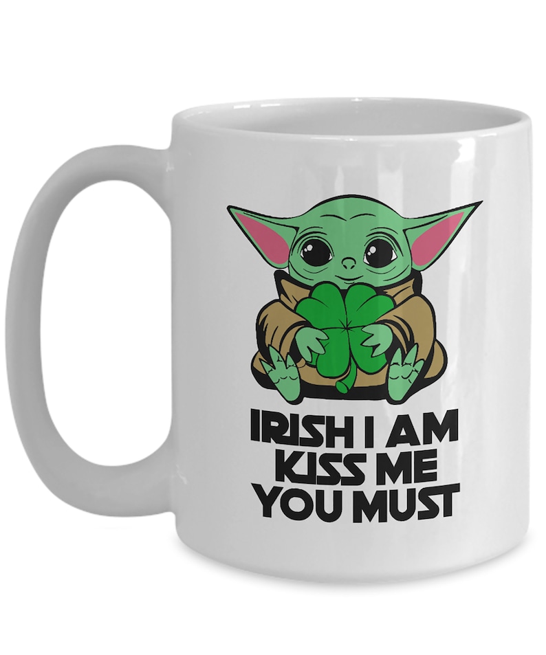 Puede incluir: Taza de cer&aacute;mica blanca con un personaje de dibujos animados verde sosteniendo un tr&eacute;bol de cuatro hojas. El texto en la taza dice "Irish I am Kiss Me You Must".