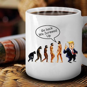 May include: White coffee mug featuring a cartoon image of human evolution with Donald Trump at the end pointing and saying "Go back We Screwed Up".