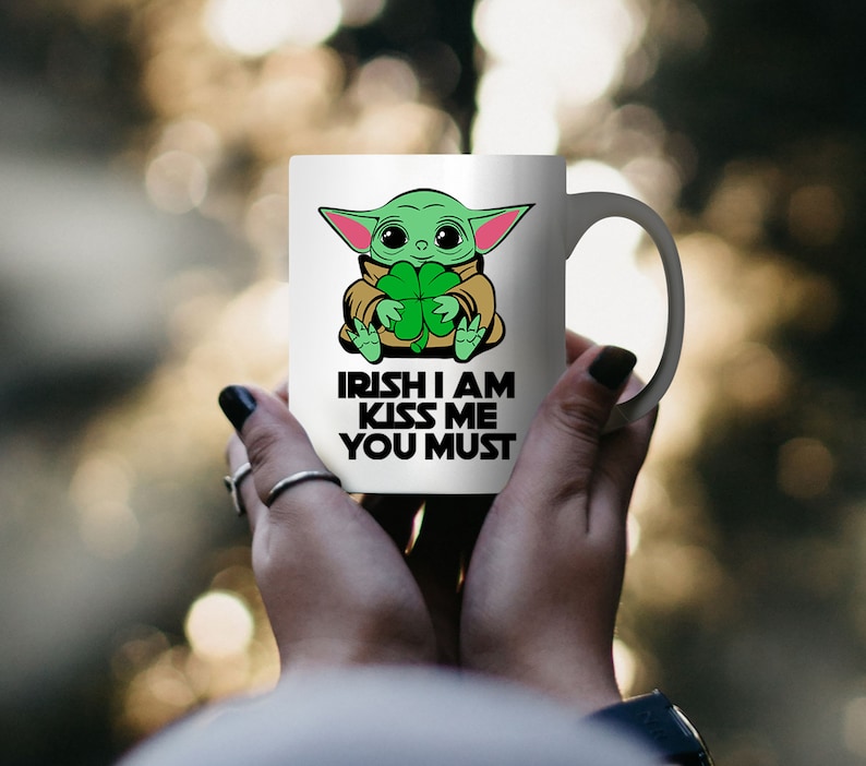 Puede incluir: Taza de cer&aacute;mica blanca con un personaje de dibujos animados verde sosteniendo un tr&eacute;bol. La taza tiene el texto "Irish I am Kiss Me You Must" impreso en ella.