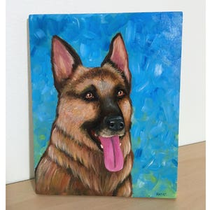 May include: A painting of a German Shepherd dog with brown fur and a pink tongue sticking out. The dog is painted against a blue background with green and white brushstrokes.