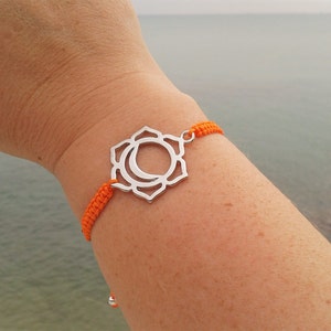 Puede incluir: Pulsera de cuerda naranja con un dije de plata que representa el símbolo del chakra sacro.
