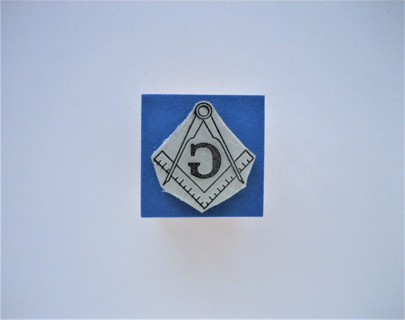 May include: A blue square with a white image of a compass and square with the letter "G" in the center.