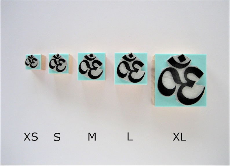 May include: Five wooden rubber stamps with a turquoise blue background and a black Om symbol. The stamps are arranged in a row from smallest to largest, labeled XS, S, M, L, and XL.